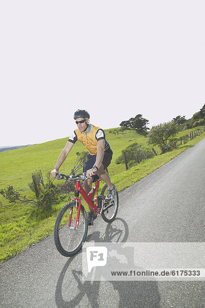 Male cyclist riding on rural road