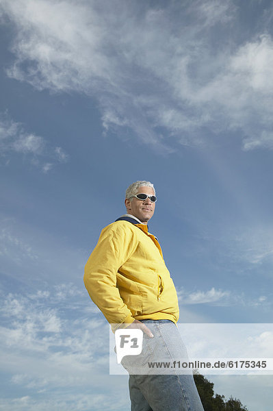 Middle-aged man standing under a blue sky with his hand in his back pocket