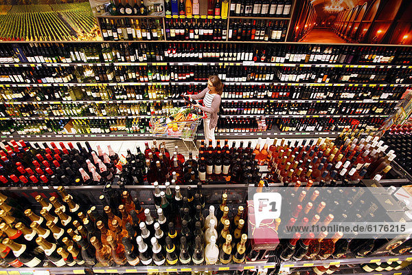 Frau beim Einkaufen in Getränkeabteilung  Sekt  Champagner  Schaumweine  Regal  Selbstbedienung  Deutschland  Europa