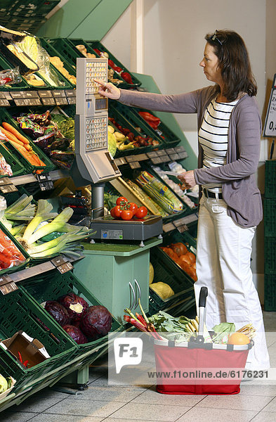 Frau wiegt Gemüse in der Gemüseabteilung ab  Selbstbedienung  Lebensmittelabteilung  Supermarkt  Deutschland  Europa