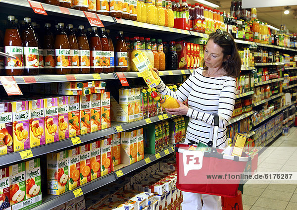 Frau schaut sich die Inhaltsstoffe einer Saftflasche an  Lebensmittelabteilung  Selbstbedienung  Supermarkt  Deutschland  Europa