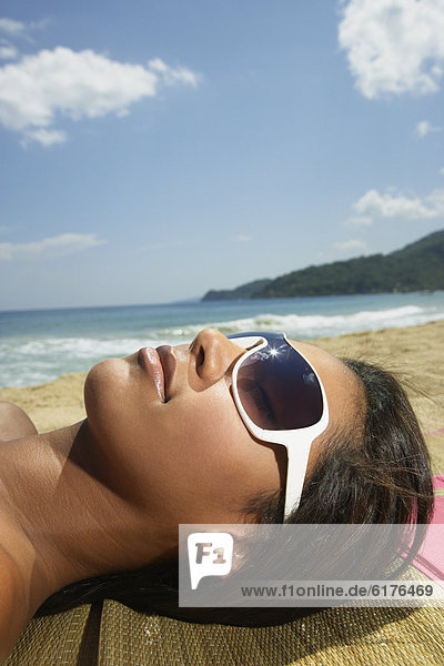 Hispanic woman laying on beach