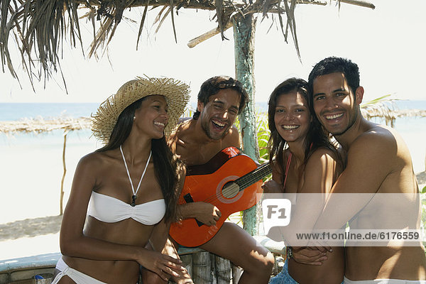 Hispanic man playing guitar for friends