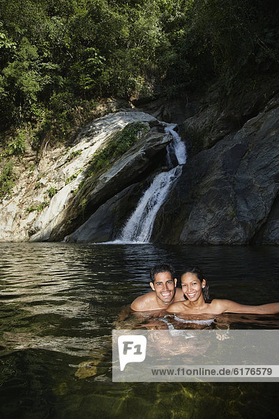 Hispanic couple swimming in water