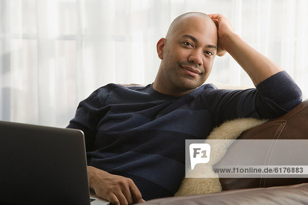 Mixed race man sitting in chair with laptop