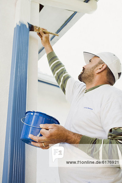 Latin man painting gutters