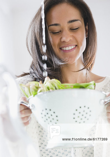 Mixed race woman rinsing spinach