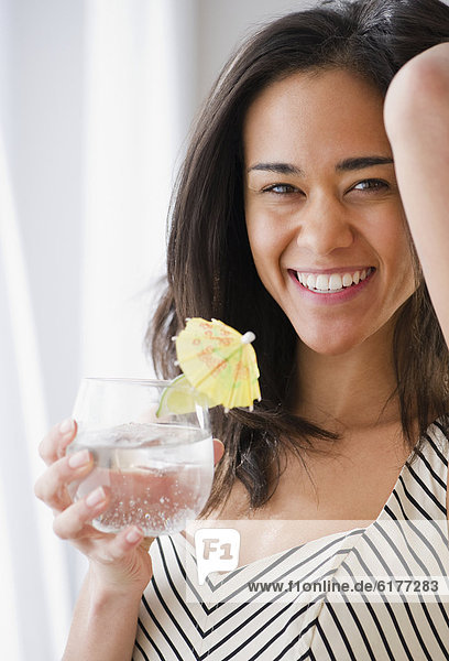 Mixed race woman drinking cocktail