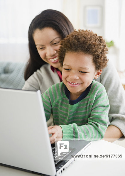 Mixed race mother using laptop with son