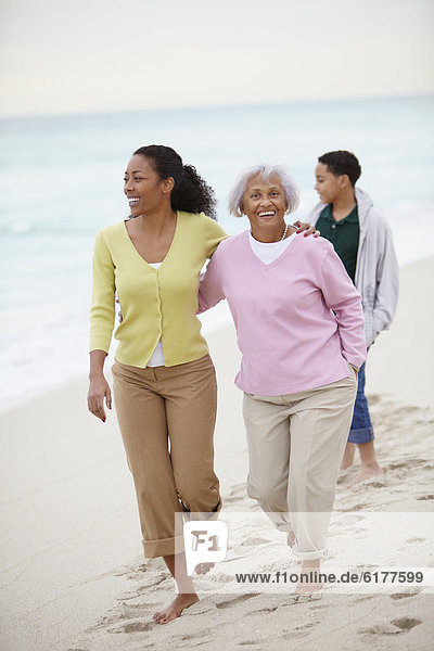 African American woman walking with mother and son on beach