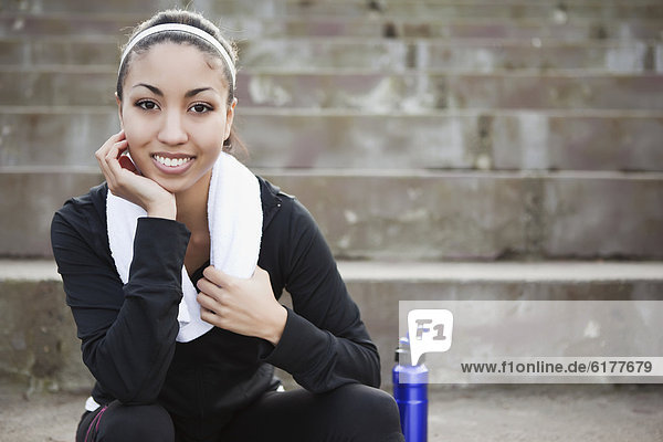 Mixed race woman sitting on steps with water bottle