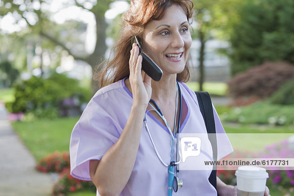 Caucasian nurse talking on cell phone in park