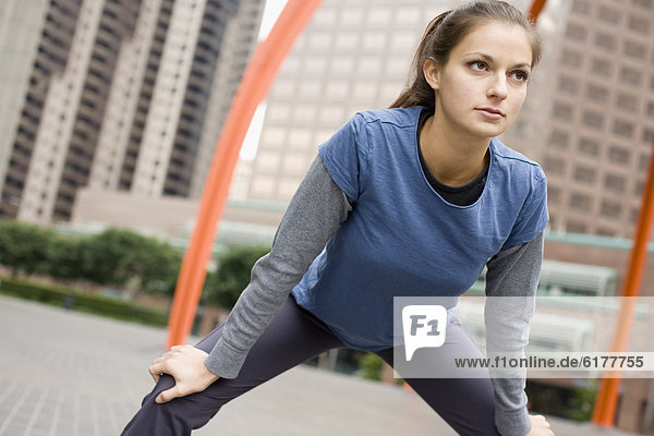 Hispanic woman stretching in urban area