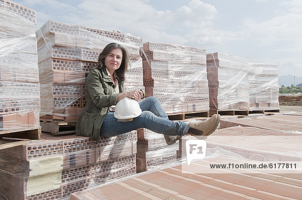 Caucasian construction worker sitting on stack of bricks