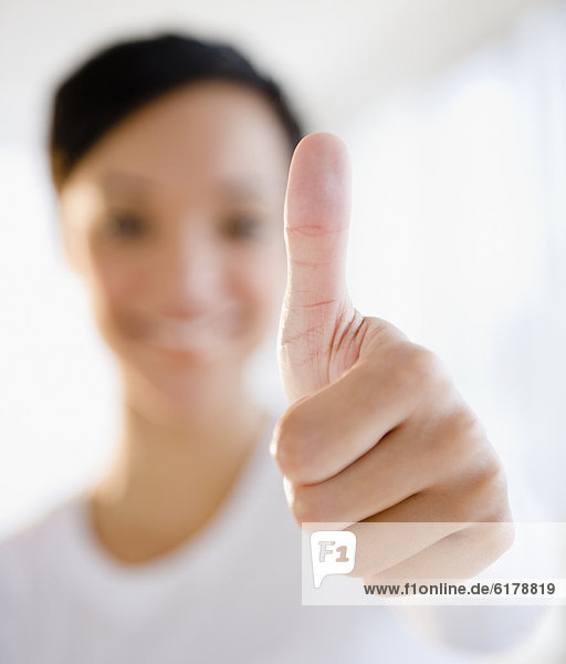 Mixed race woman giving thumbs up sign