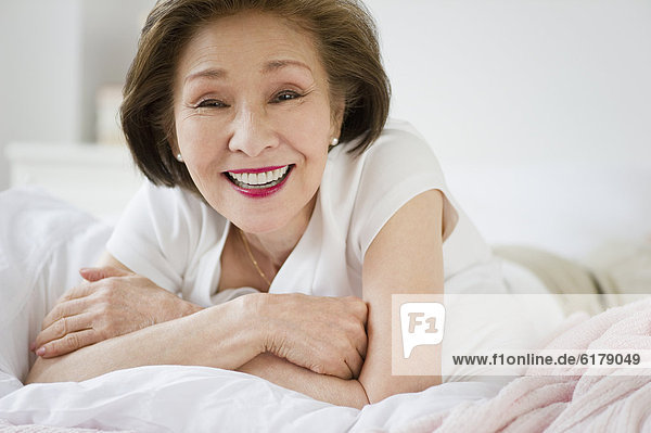 Japanese woman laying in bed smiling