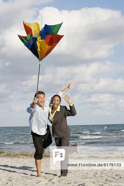 Hispanic businesspeople holding broken beach umbrella