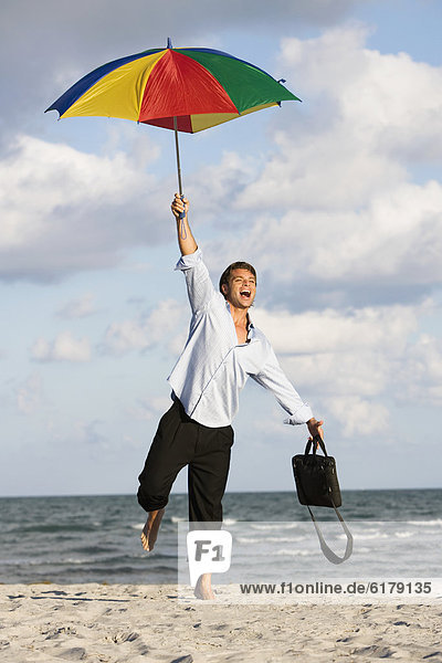 Hispanic businessman holding beach umbrella