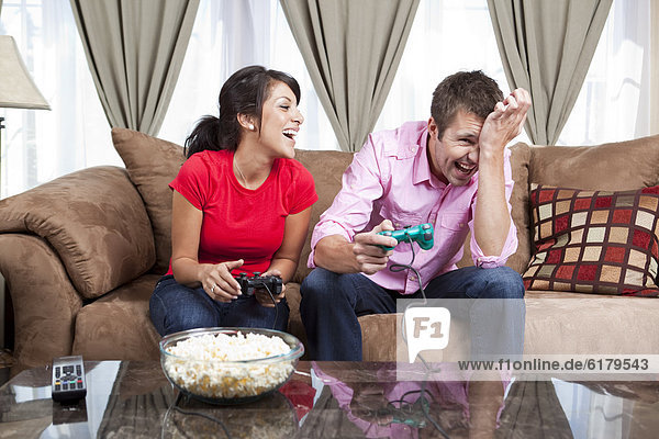 Couple sitting on sofa and playing video game