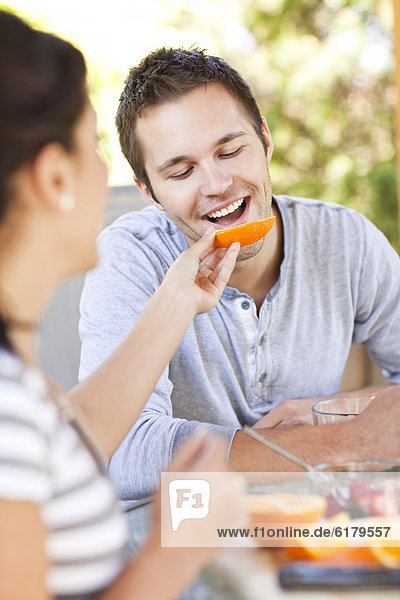 Woman feeding orange to man
