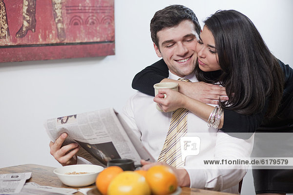 Couple eating breakfast and reading newspaper