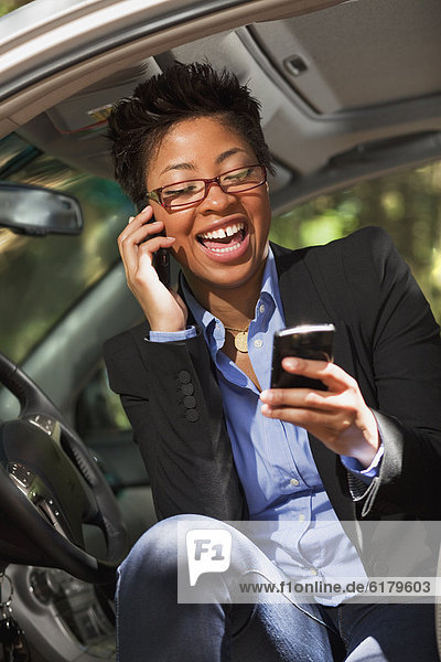 Black woman in vehicle using two cell phones
