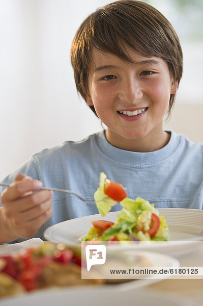 Smiling mixed race boy eating salad