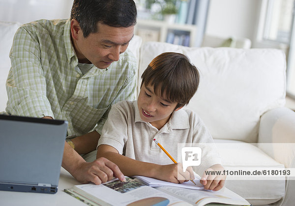 Father helping son with homework in living room