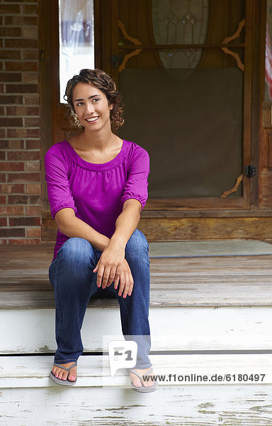 Mixed race woman sitting on front stoop