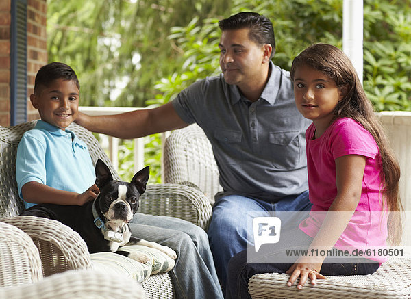 Father and children sitting on porch with dog