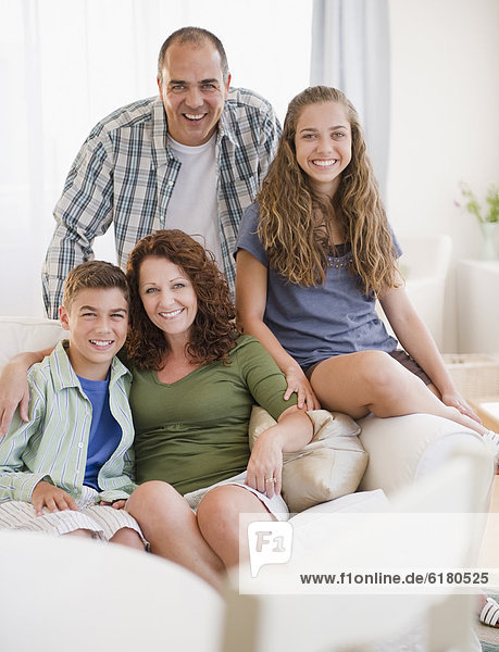 Smiling Hispanic family sitting on sofa together
