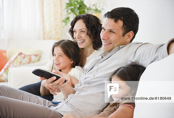 Happy family sitting on sofa watching television