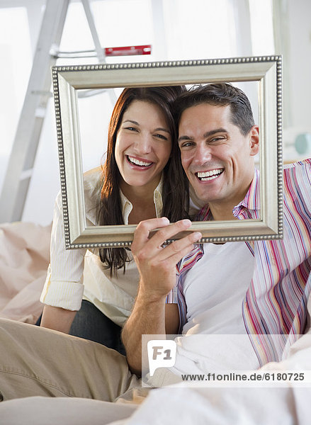 Smiling couple looking through empty frame