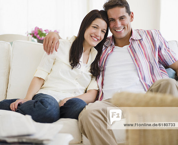 Smiling couple sitting on sofa together