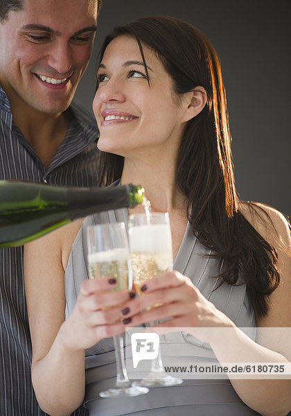 Smiling man pouring Champagne for girlfriend