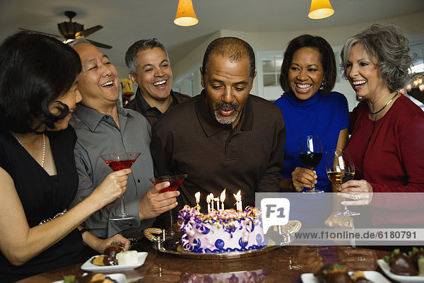 African man celebrating birthday with multi-ethnic friends