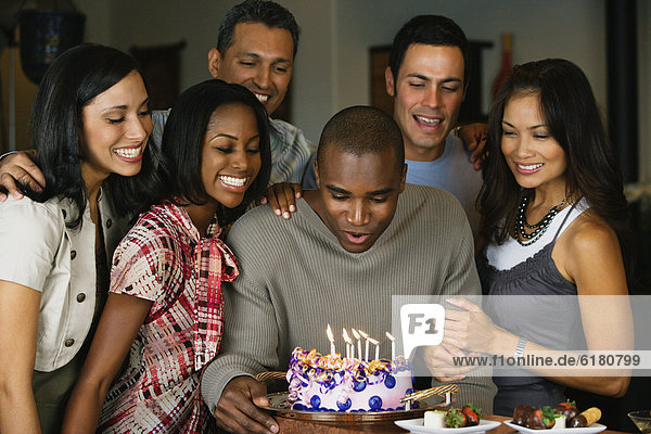 African man celebrating birthday with multi-ethnic friends