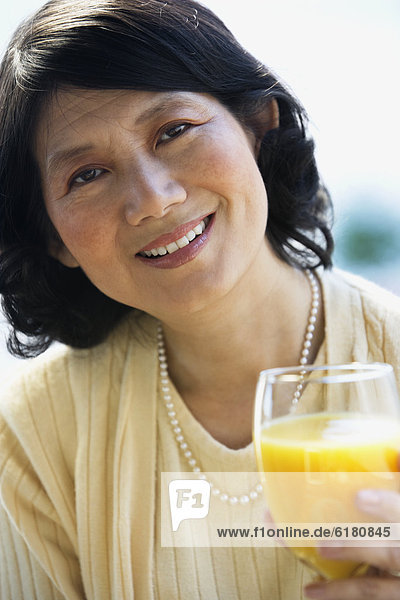 Asian woman drinking orange juice