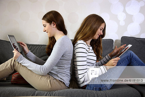 Two girls playing at home with an iPad  tablet computer  wireless internet access