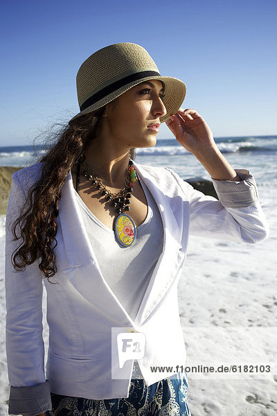Mixed race woman wearing hat at beach