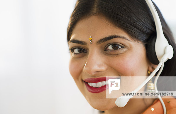 Mixed race woman in traditional Indian clothing talking on headset