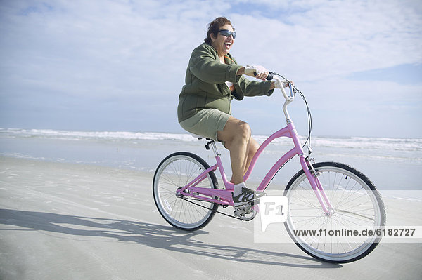 Senior Italian woman riding bicycle on beach