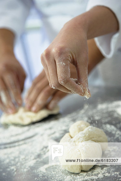 Close up of baker sprinkling flour on dough