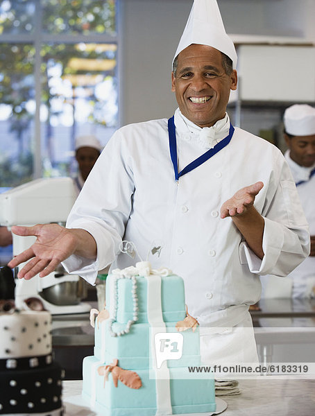 Mixed Race male pastry chef next to cake