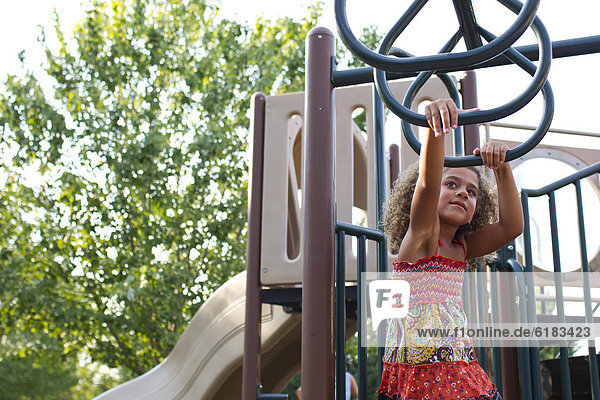 Mixed race girl playing on playground