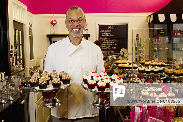 African American small business owner with cupcakes in bakery shop