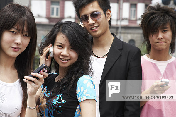Chinese friends text messaging and talking on cell phones