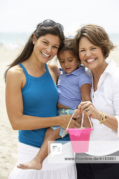 Hispanic grandmother  mother and daughter enjoying beach
