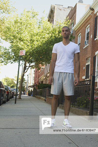Mixed race man standing on urban sidewalk