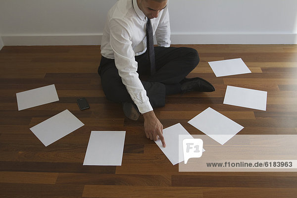 Mixed race businessman choosing paper on floor
